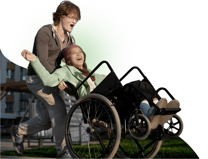 Foto representando uma mulher em uma cadeira de rodas sorridente ao ser empurrada de forma divertida por um homem representando os laços e acolhimento oferecidos pela clinica de reabilitação Nuren.